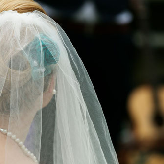 Braut mit Schleier und türkisen Blumen im Haar von hinten
