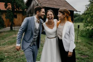 Ein strahlendes Brautpaar mit Traurednerin Veronika Bracks von Strauß & Fliege