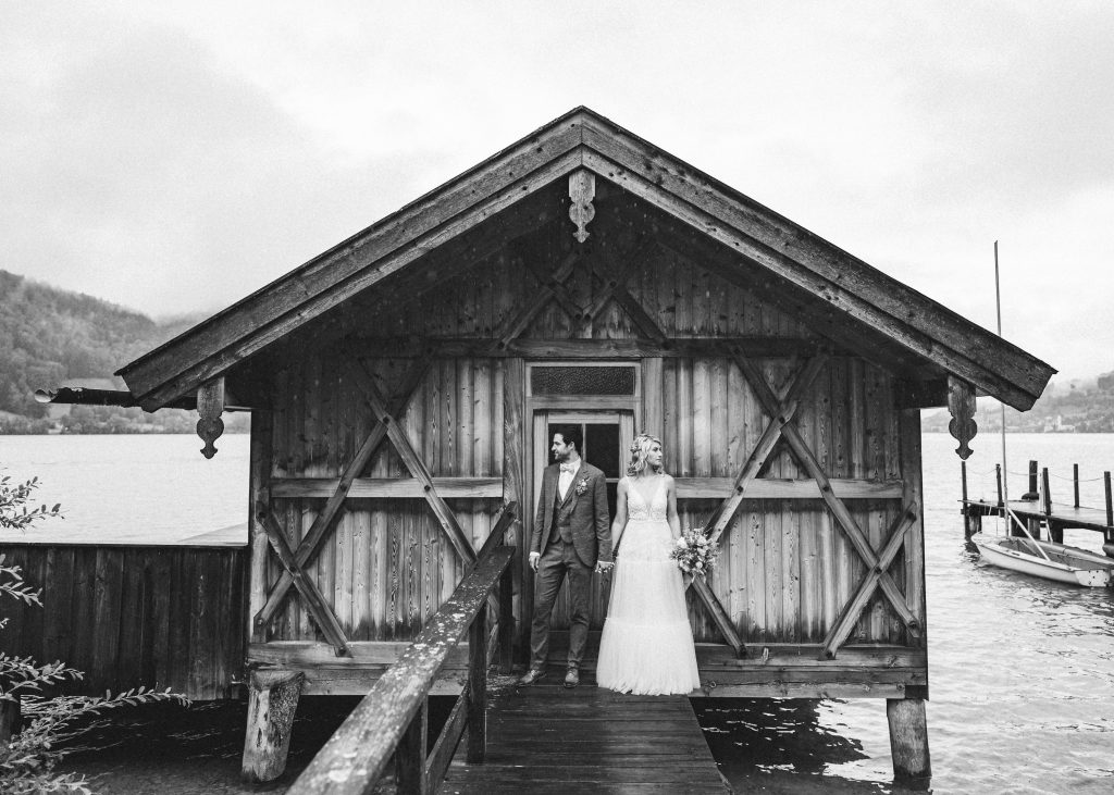 Brautpaar vor Holzhütte auf dem Steg am See