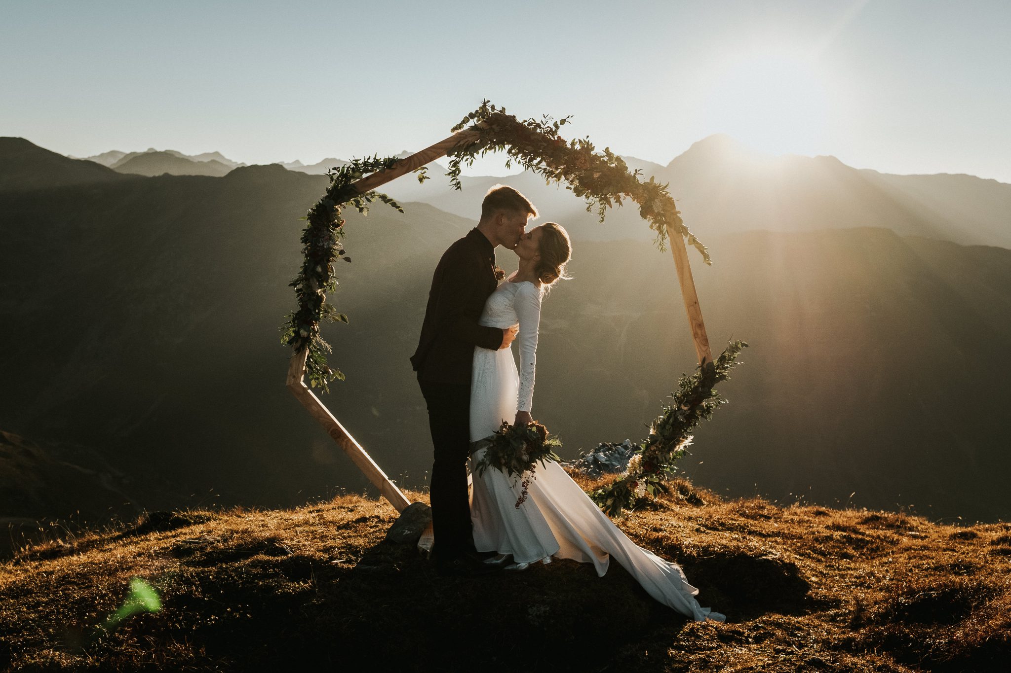 Brautpaar unter Blumenbogen auf einer Bergspitze mit Panoramablick
