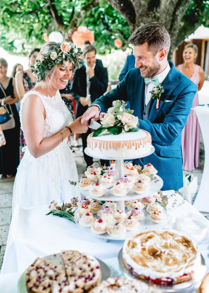 Brautpaar beim Anschneiden der Hochzeitstorte | Strauß & Fliege