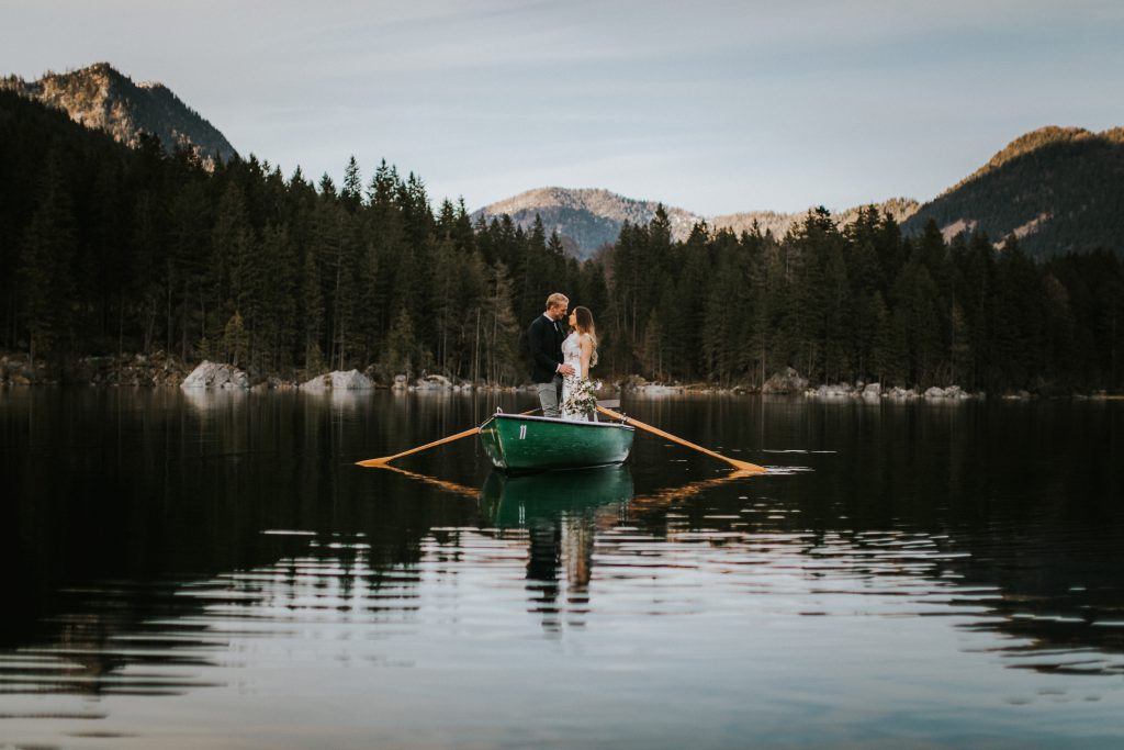 Brautpaar in Holzboot auf einem einsamen Gebirgssee