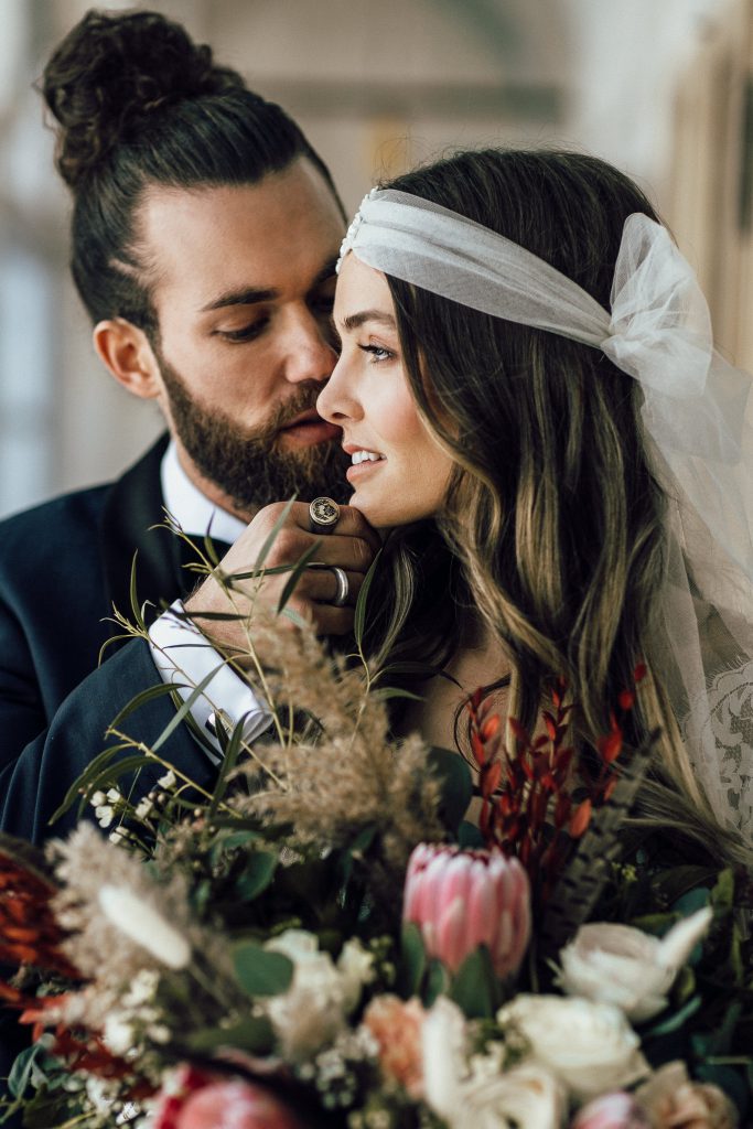 Braut mit Kopfschmuck und Blumen und Bräutigam