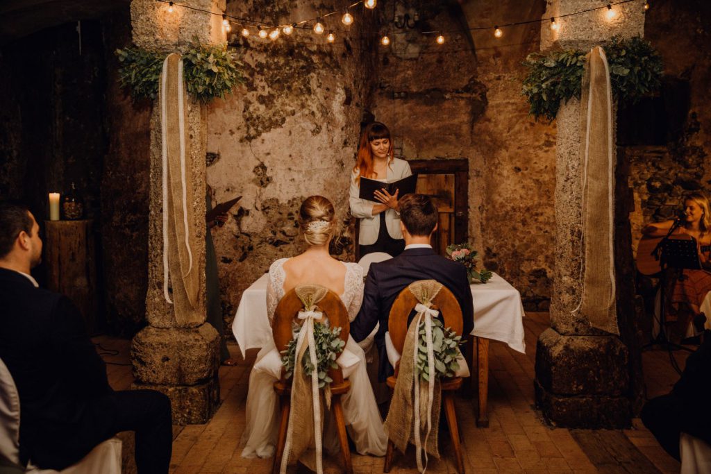 Hochzeitsrednerin Veronika Bracks mit einem Brautpaar in einem Kellergewölbe