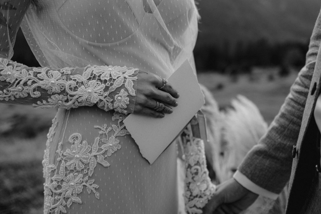 Braut im Boho Brautkleid hält ihr Eheversprechen in der Hand