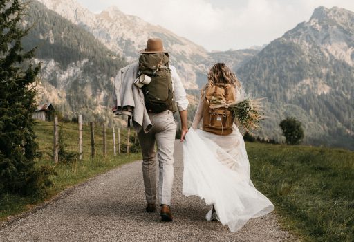 Brautpaar mit Wanderrucksäcken beim Spaziergang in den Bergen