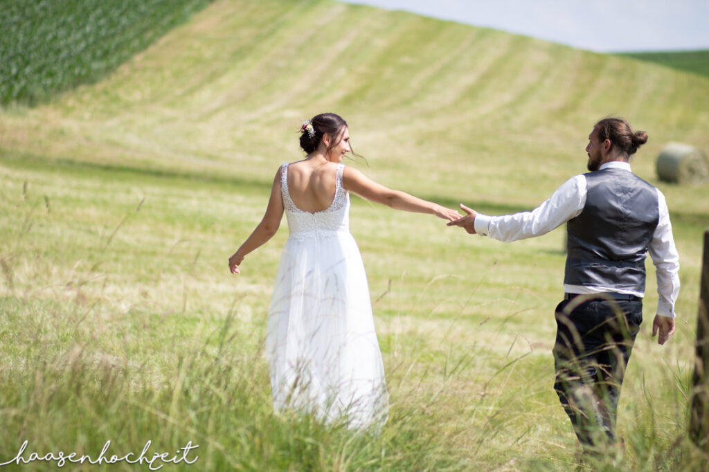 Brautpaar flaniert über Sommerwiese